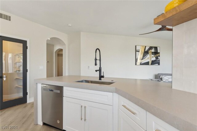 kitchen featuring visible vents, light countertops, stainless steel dishwasher, white cabinetry, and a sink