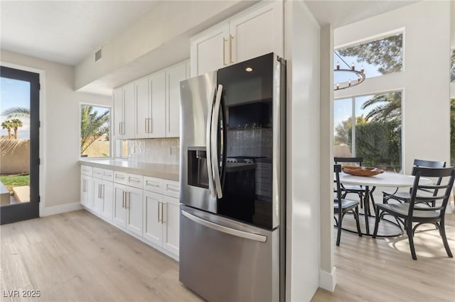 kitchen featuring light wood-style flooring, decorative backsplash, light countertops, white cabinets, and stainless steel refrigerator with ice dispenser