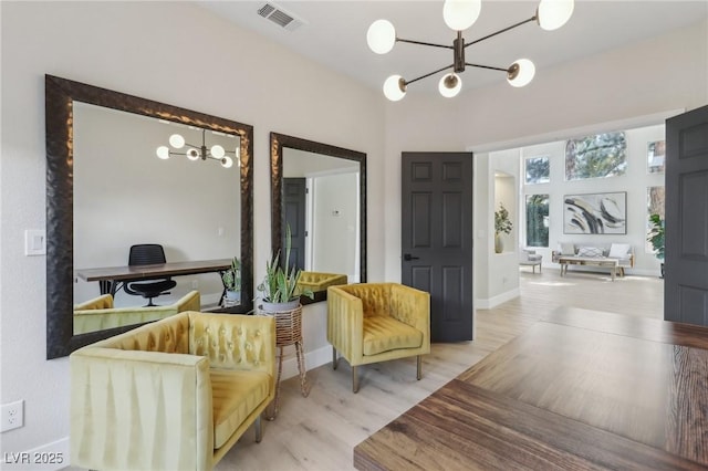 living area with visible vents, baseboards, an inviting chandelier, and wood finished floors