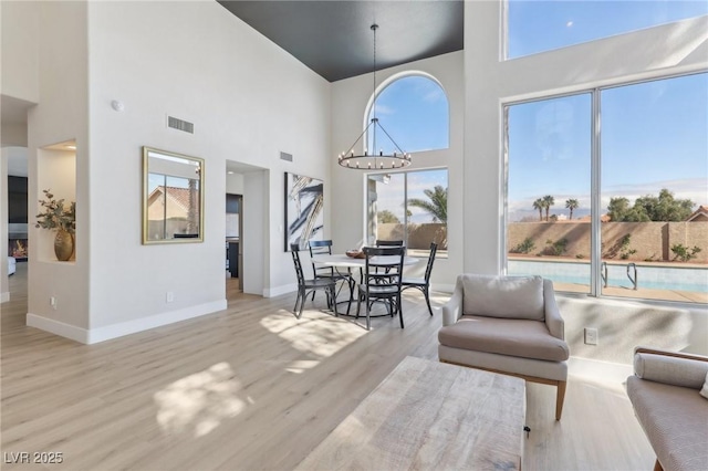 living room with visible vents, baseboards, a notable chandelier, and wood finished floors