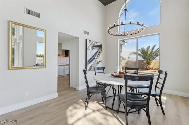 dining space with a chandelier, visible vents, baseboards, and wood finished floors