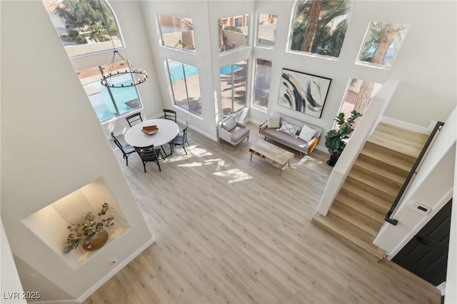 interior space with stairway, a high ceiling, baseboards, and wood finished floors