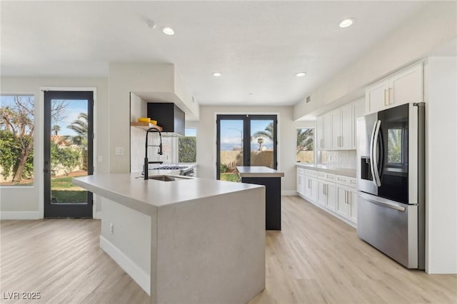 kitchen with a healthy amount of sunlight, stainless steel refrigerator with ice dispenser, light wood finished floors, and a sink