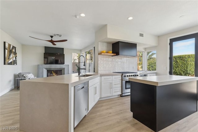 kitchen with a sink, stainless steel appliances, open shelves, and light countertops