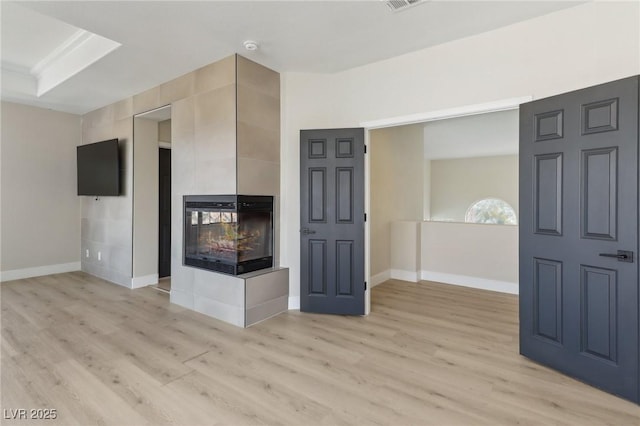 unfurnished living room with baseboards, light wood-style floors, and a tiled fireplace