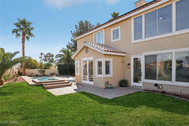 rear view of property with stucco siding, a lawn, a fenced backyard, and a patio area