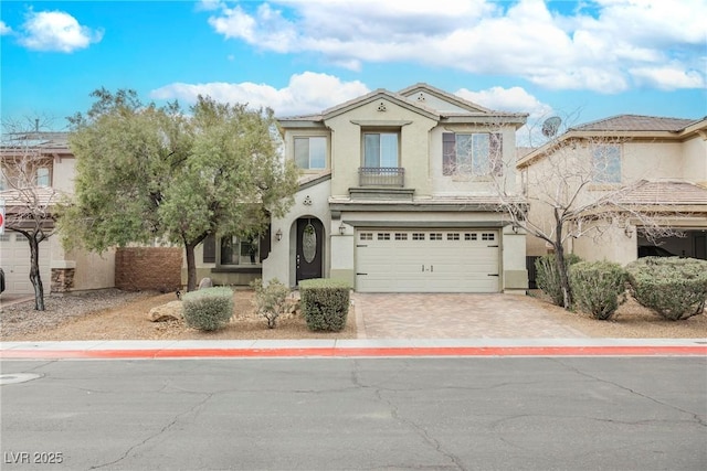 view of front of home with stucco siding, an attached garage, and decorative driveway