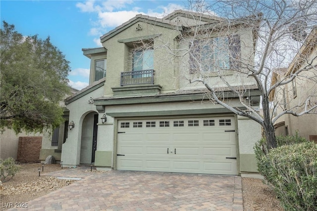 view of front of house with stucco siding, a tile roof, decorative driveway, and a garage