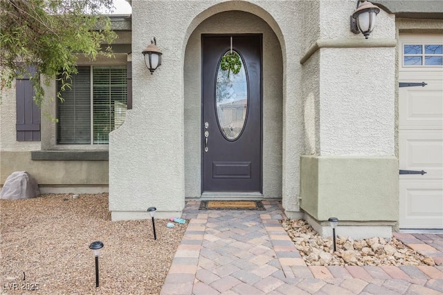 doorway to property featuring stucco siding and a garage