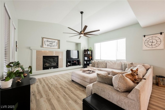 living room with ceiling fan, lofted ceiling, wood finished floors, and a high end fireplace