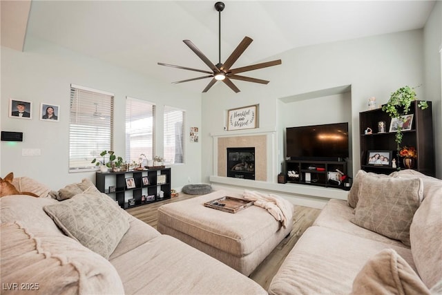 living area with a premium fireplace, wood finished floors, ceiling fan, and vaulted ceiling