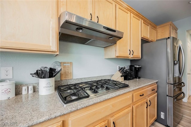 kitchen featuring under cabinet range hood, light stone countertops, stainless steel appliances, and light brown cabinetry