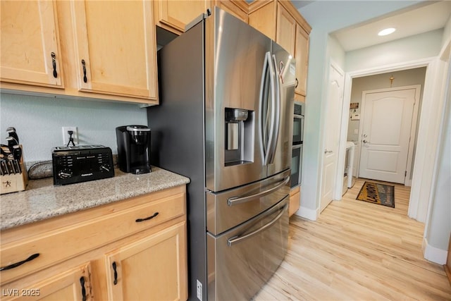 kitchen featuring light brown cabinetry, light wood-type flooring, light stone counters, recessed lighting, and stainless steel fridge