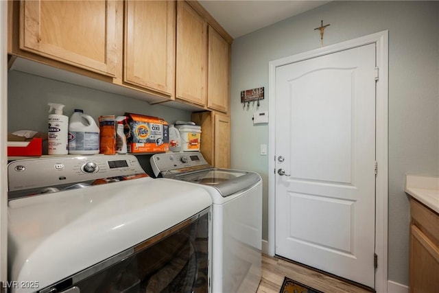 clothes washing area featuring washer and dryer, cabinet space, and light wood-style floors