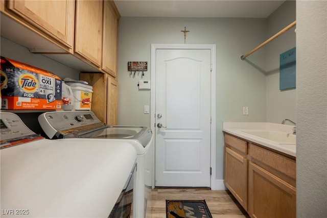 washroom with washing machine and clothes dryer, light wood-style flooring, cabinet space, and a sink