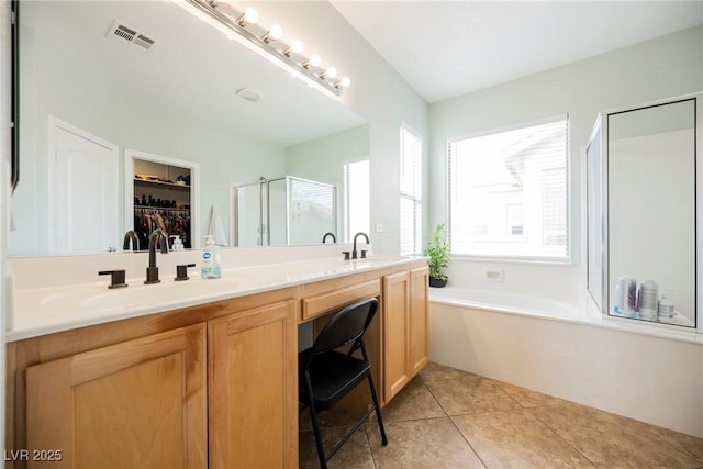 full bath featuring visible vents, double vanity, a stall shower, a sink, and tile patterned flooring