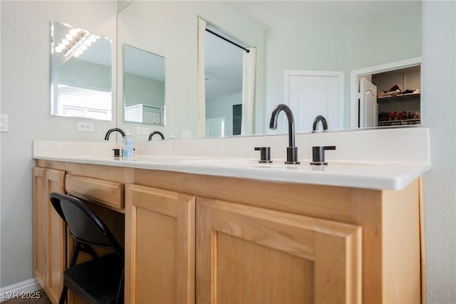 full bath featuring a sink, baseboards, and double vanity