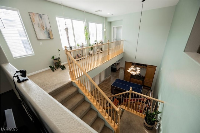 staircase featuring a notable chandelier, visible vents, baseboards, and carpet floors