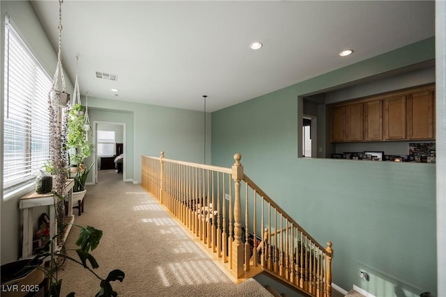 corridor featuring baseboards, visible vents, recessed lighting, light carpet, and an upstairs landing