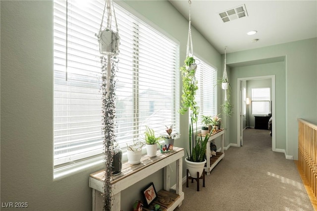 hallway with visible vents, baseboards, and carpet