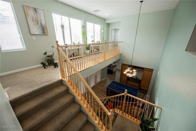 stairway featuring a notable chandelier, baseboards, visible vents, and carpet floors