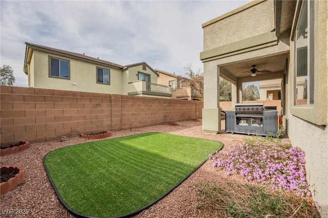 view of yard with area for grilling, ceiling fan, and a fenced backyard