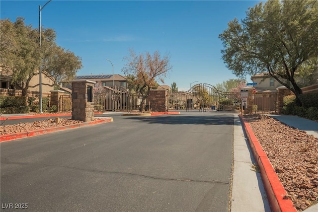 view of street with a gate, curbs, and a gated entry