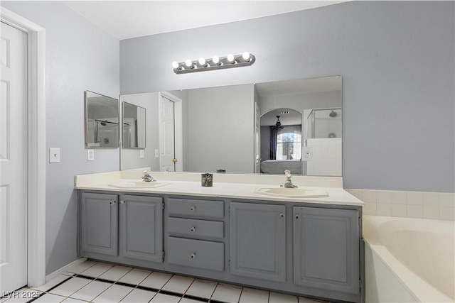 bathroom featuring a bath, a shower stall, double vanity, and a sink