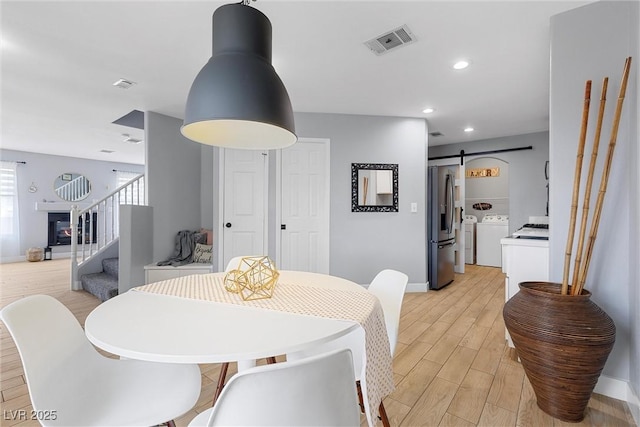 dining area with stairs, a barn door, separate washer and dryer, and visible vents