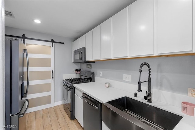 kitchen featuring white cabinetry, black appliances, a barn door, and light countertops