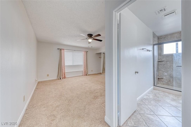 interior space featuring visible vents, a textured ceiling, baseboards, light colored carpet, and ceiling fan