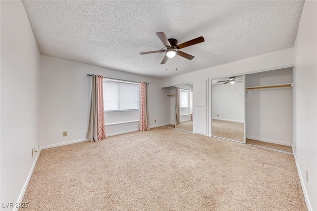 unfurnished bedroom with baseboards, multiple closets, carpet, and a textured ceiling