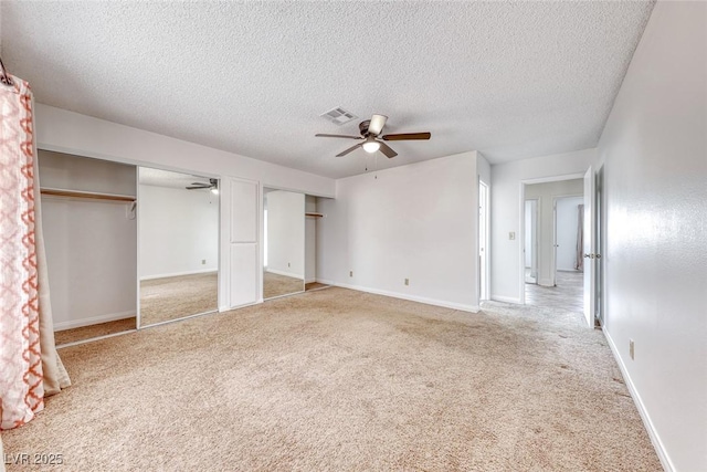 unfurnished bedroom with light carpet, visible vents, baseboards, and multiple closets