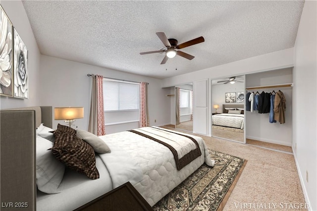 carpeted bedroom featuring baseboards, multiple closets, a textured ceiling, and ceiling fan