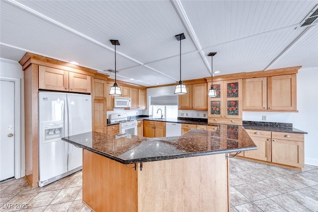 kitchen featuring white appliances, dark stone countertops, visible vents, a sink, and a center island