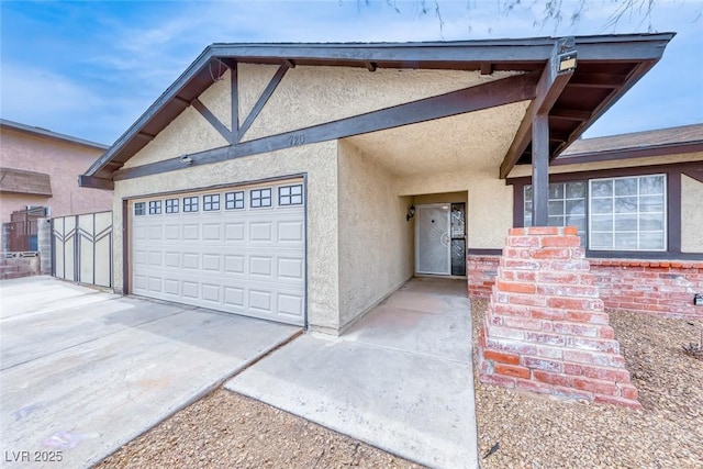 view of front of home with stucco siding, concrete driveway, a garage, and fence