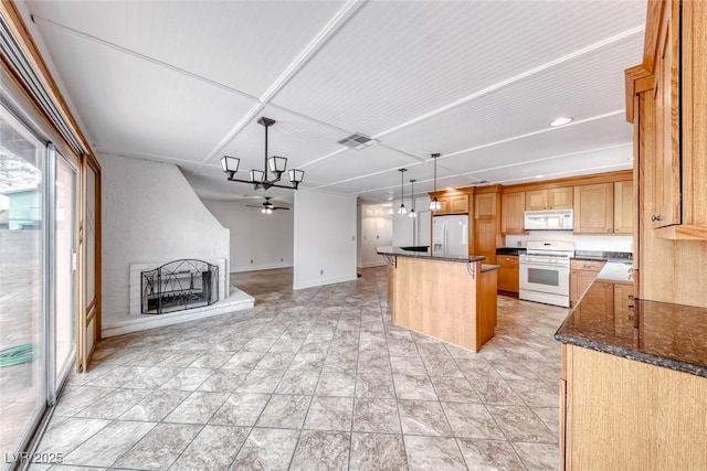 kitchen featuring white appliances, a ceiling fan, a kitchen island, open floor plan, and a large fireplace