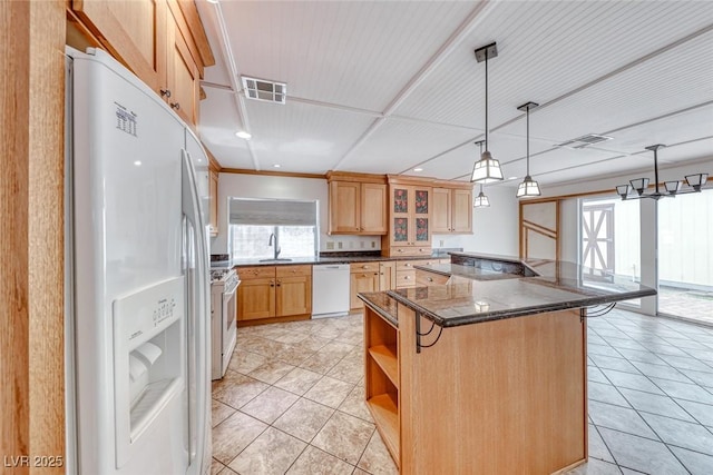 kitchen featuring white appliances, a breakfast bar area, visible vents, a kitchen island, and a sink