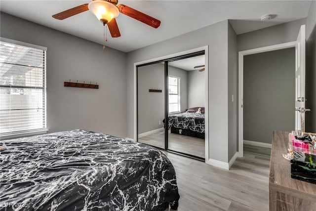 bedroom featuring a closet, light wood-style flooring, a ceiling fan, and baseboards