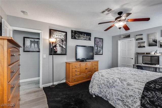 bedroom with visible vents, a ceiling fan, baseboards, and wood finished floors