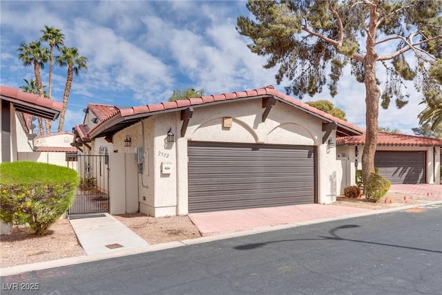 view of front of house featuring a gate, stucco siding, a garage, and a tile roof