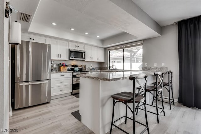 kitchen featuring a tray ceiling, visible vents, appliances with stainless steel finishes, and a sink