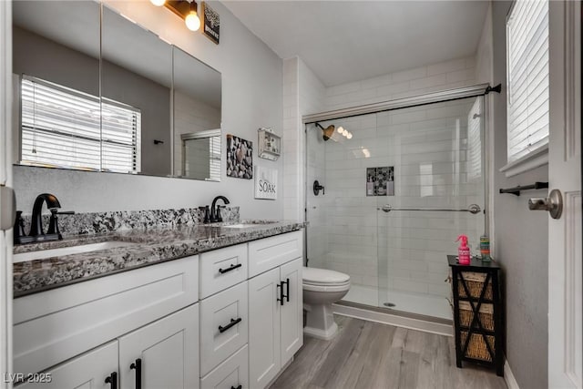 full bathroom with a sink, double vanity, wood finished floors, and a shower stall