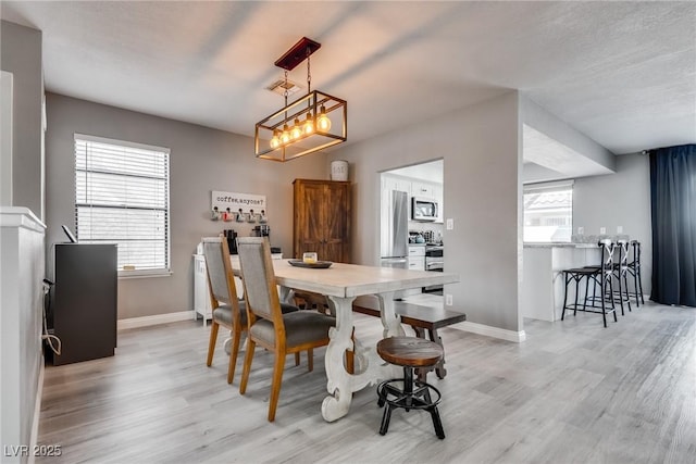 dining area featuring an inviting chandelier, visible vents, light wood-style floors, and baseboards