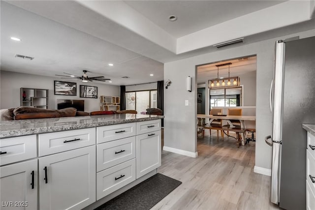 kitchen with light wood finished floors, open floor plan, freestanding refrigerator, and visible vents