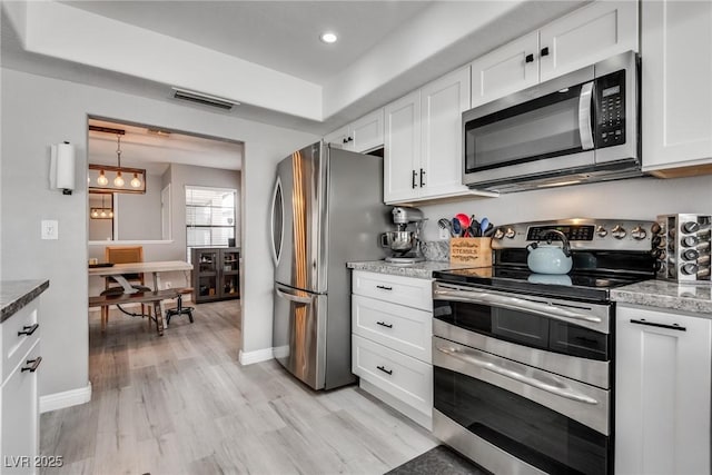 kitchen featuring visible vents, white cabinetry, stainless steel appliances, and light wood-style floors