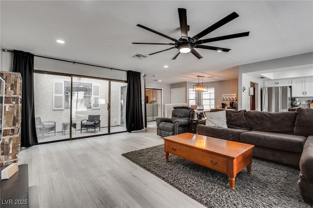 living room featuring recessed lighting, visible vents, light wood finished floors, and ceiling fan with notable chandelier