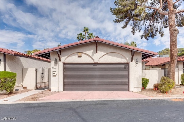 mediterranean / spanish house with stucco siding, a gate, fence, a garage, and a tiled roof