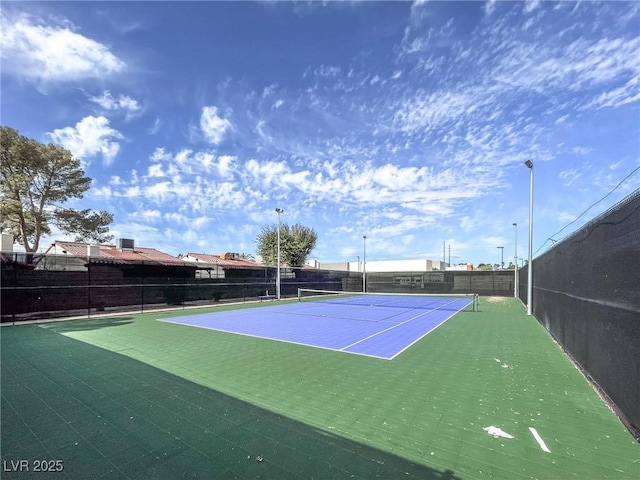 view of tennis court featuring community basketball court and fence