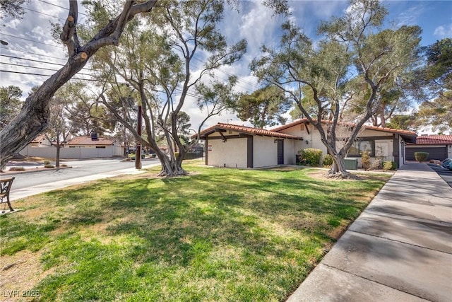 view of front of property with stucco siding, a front yard, and a tiled roof